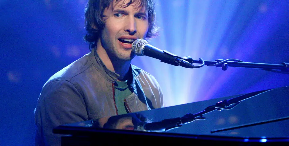 James Blunt singing and playing piano during a live concert performance.
James Blunt singing and playing piano during concert performance