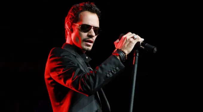 Marc Anthony singing on stage wearing sunglasses and black suit
