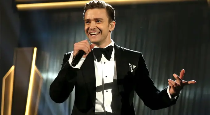 Justin Timberlake wearing tuxedo, singing on stage with microphone