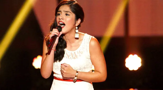 Woman in white dress passionately singing on stage with microphone