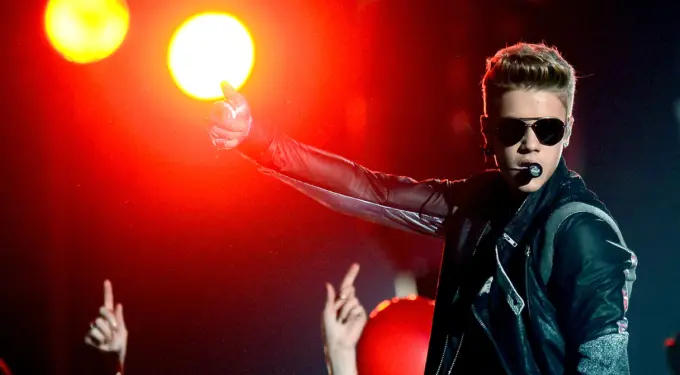Justin Bieber in sunglasses performs onstage with red lights