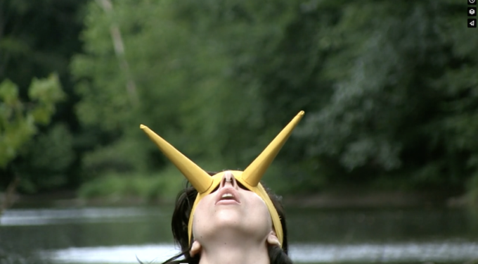 Lady Gaga wearing a yellow horned headpiece outdoors near water