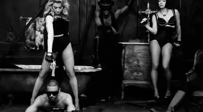 Madonna in black outfit holding gun, two women and man with rifle