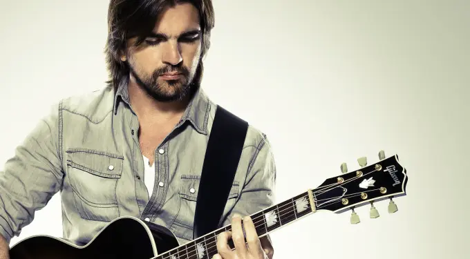 Colombian musician Juanes playing acoustic guitar, focused look