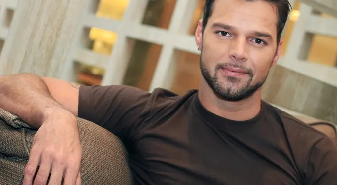 Ricky Martin relaxed sitting on couch looking directly at camera