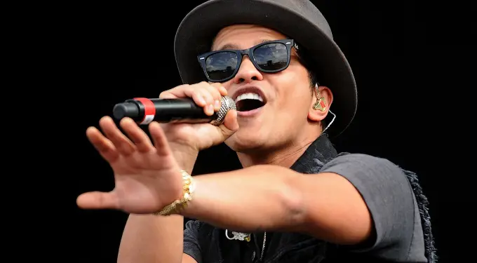 Bruno Mars singing into microphone wearing sunglasses and hat