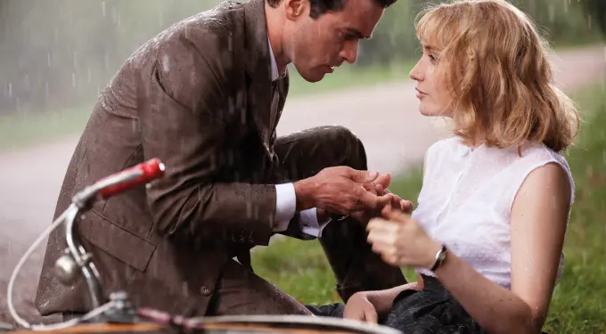 man in suit holding woman's hand while it rains outside