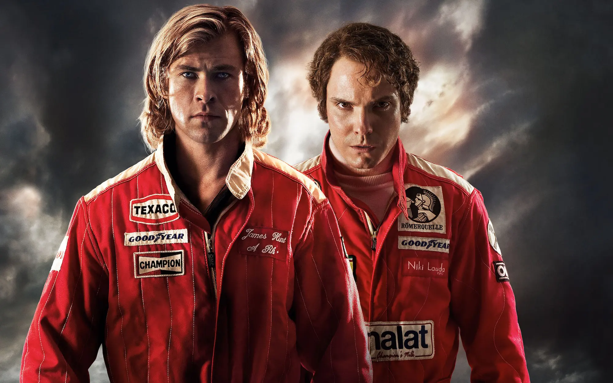 Chris Hemsworth and Daniel Brühl in racing suits face camera seriously