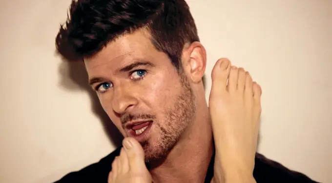 Robin Thicke close-up lip syncing with foot next to his face