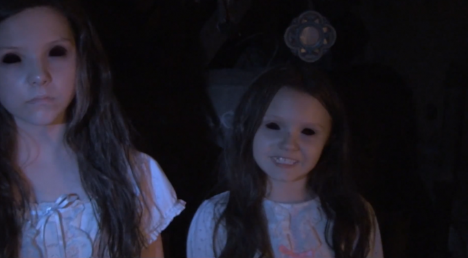 Two young girls with blacked-out eyes in dark, eerie setting