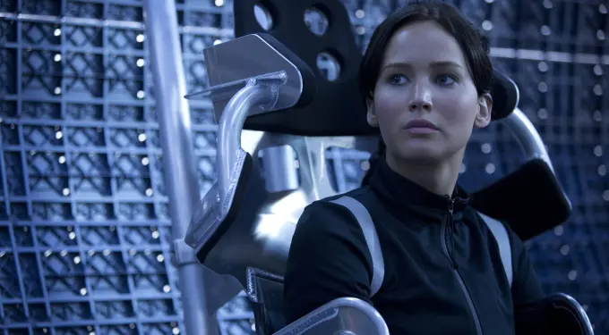 Jennifer Lawrence seated in futuristic chair looking serious and thoughtful
