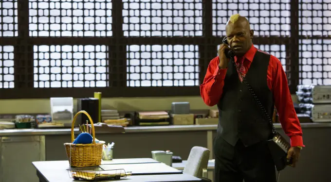 Samuel L. Jackson on phone wearing red shirt and black vest in office
