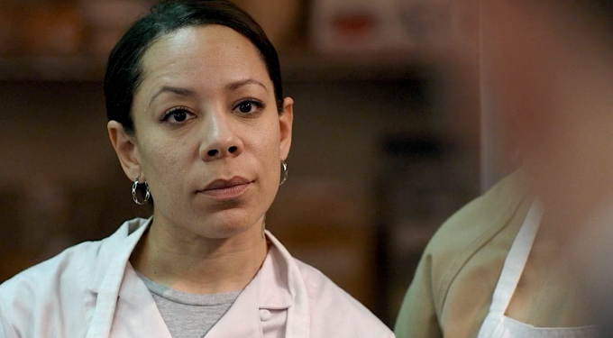 Selenis Leyva close-up wearing apron in serious scene