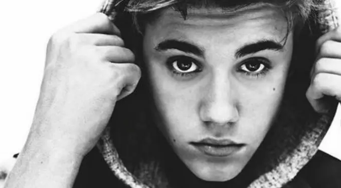 Black and white close-up of Justin Bieber holding hoodie strings