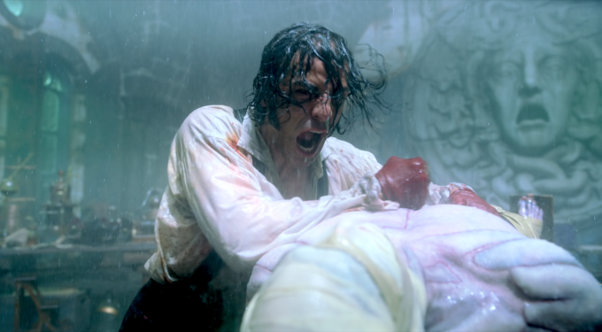 Oscar Isaac screams leaning over bound figure in rain in Frankenstein