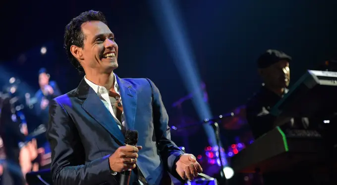 Marc Anthony smiling and holding microphone on stage during concert