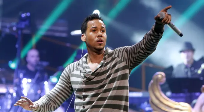 Romeo Santos singing and pointing with microphone on stage