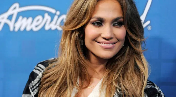 Jennifer Lopez smiling in front of blue American Idol backdrop