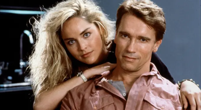 Blonde woman embraces man in pink shirt in Total Recall still