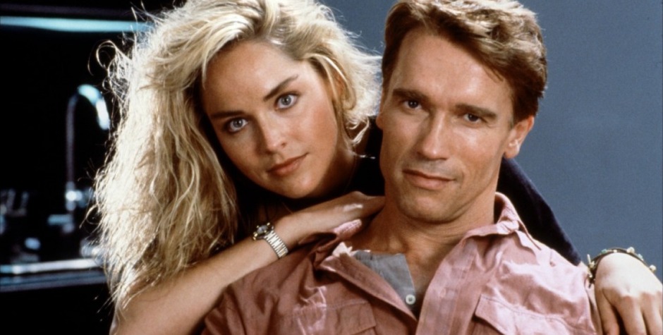 Blonde woman embraces man in pink shirt in Total Recall still
