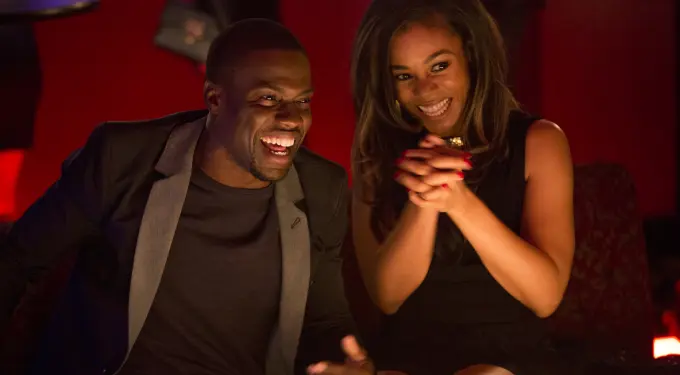 Kevin Hart and Regina Hall laughing together in a dark room
