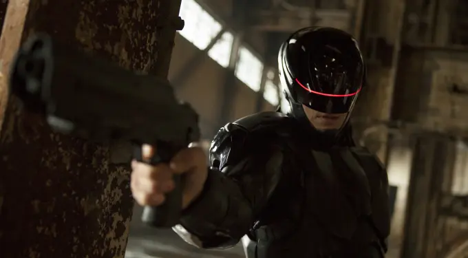 RoboCop in black armor aiming gun in dark industrial location