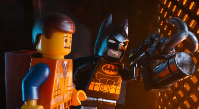 Lego Batman holds mechanical claw next to worried Lego Emmet