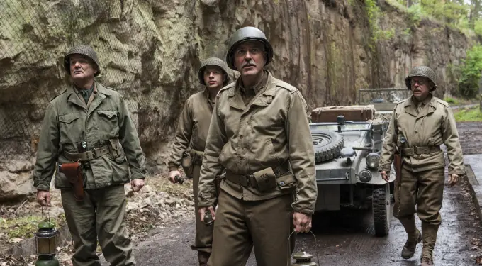 Four World War II soldiers in uniform with helmets and lanterns by jeep