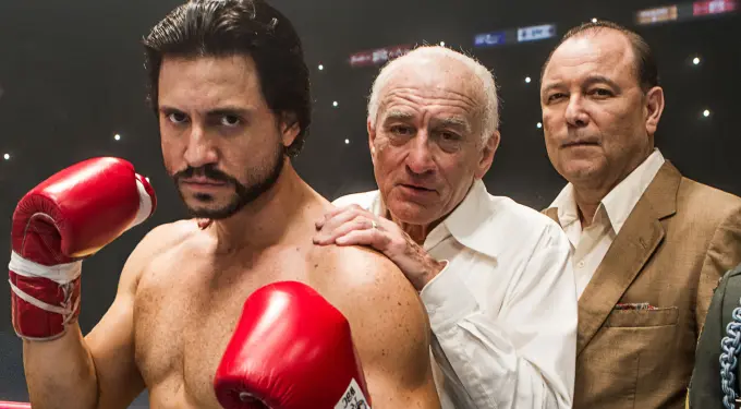 Boxer with red gloves posed with two men behind in boxing ring