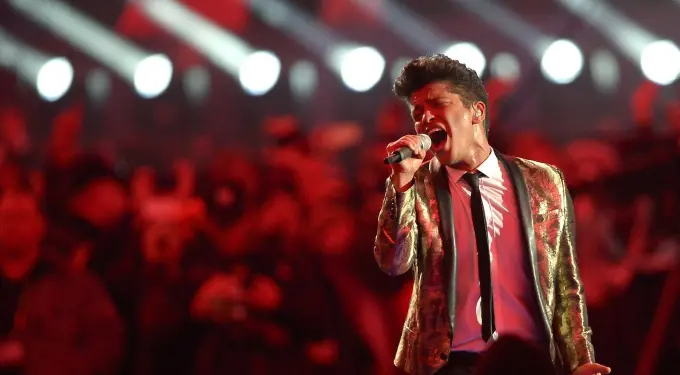 Bruno Mars singing energetically at Super Bowl halftime in gold jacket