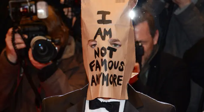 Shia LaBeouf with paper bag saying 'I AM NOT FAMOUS ANYMORE' on red carpet