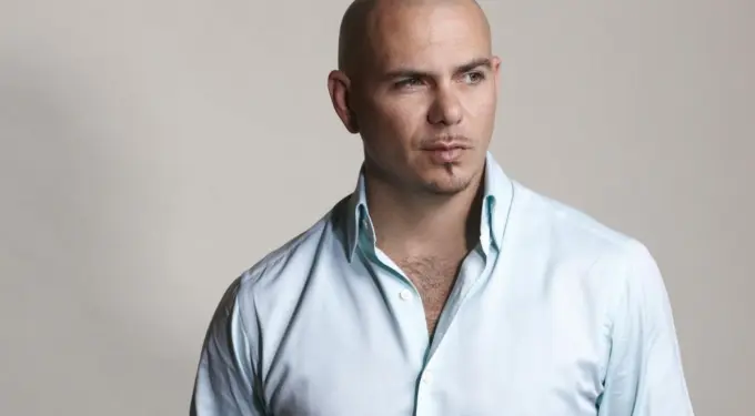 Pitbull in light blue shirt looking off to the side against plain background