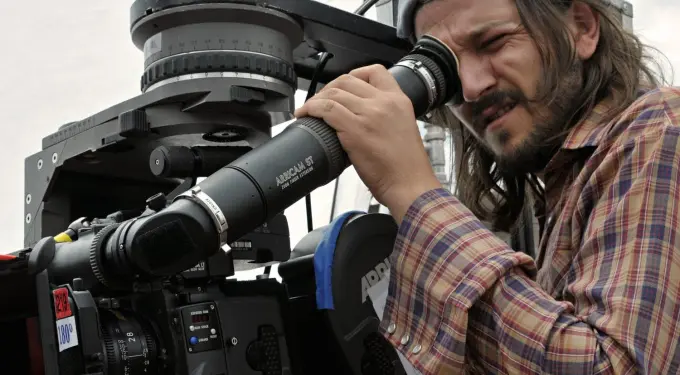 Diego Luna looking through camera lens directing a film