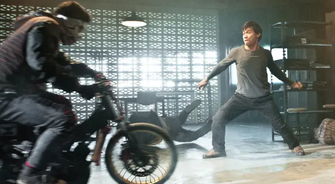 man defends against motorcycle rider in warehouse fight scene