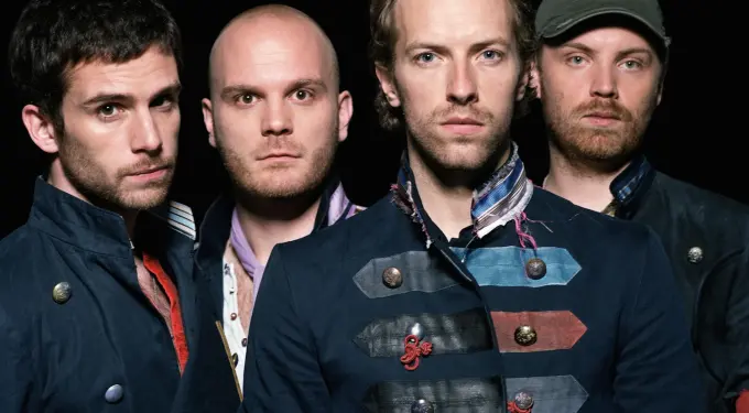 Coldplay band members in military style jackets pose against black background