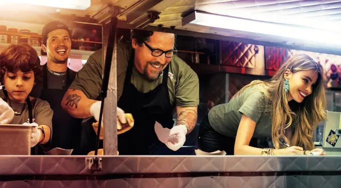 Four food truck workers prepare and serve food smiling and focused
