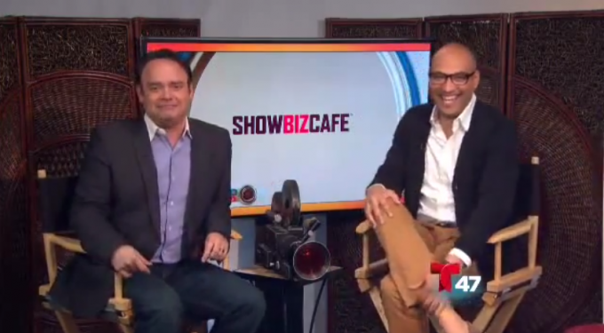 Two men seated in director chairs with ShowBizCafe screen behind them
