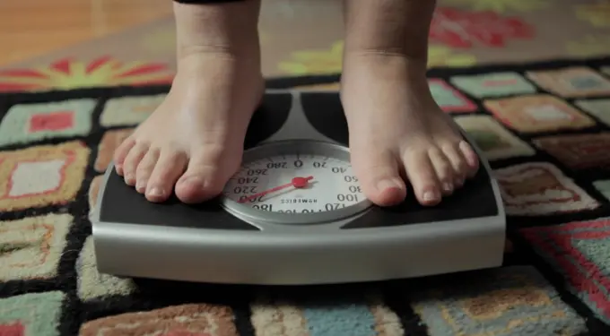 Closeup of feet standing on weight scale on colorful rug