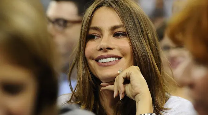 Sofia Vergara smiling with hand under chin at an indoor event