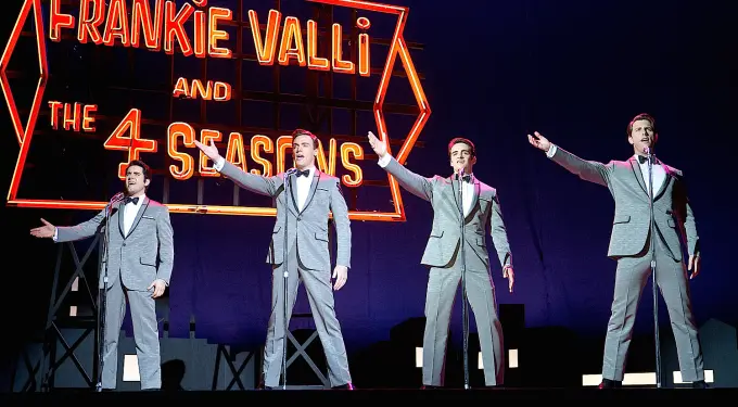Four male performers in suits singing on stage at Jersey Boys show