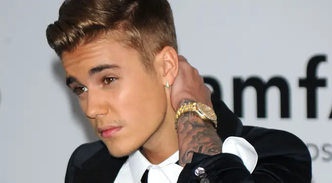 Justin Bieber adjusting collar with tattooed arm and watch visible