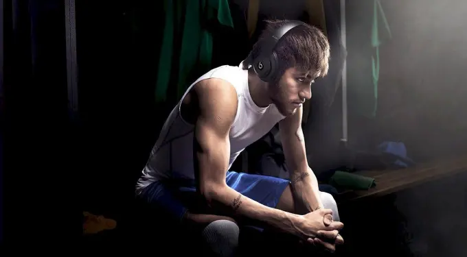 Neymar Jr. in white sleeveless shirt and blue shorts wearing headphones