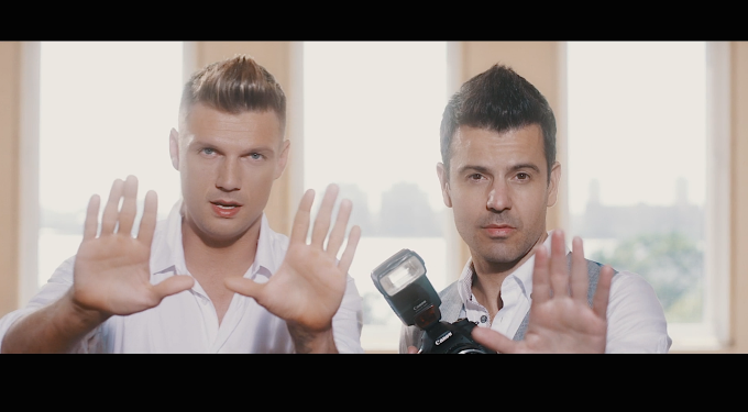 Nick and Knight hold hands up to camera in music video scene