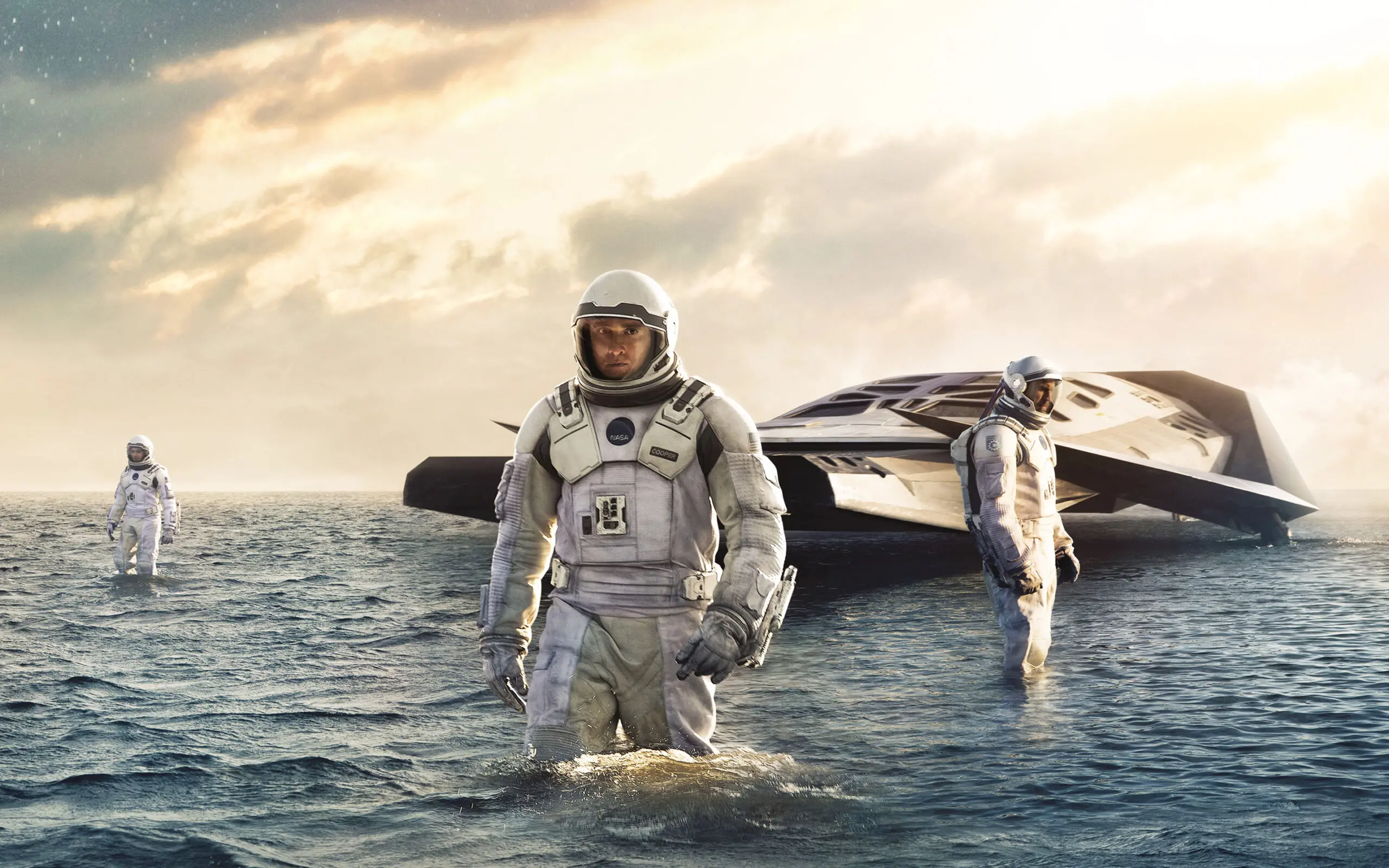 three astronauts in spacesuits standing in water near futuristic spacecraft