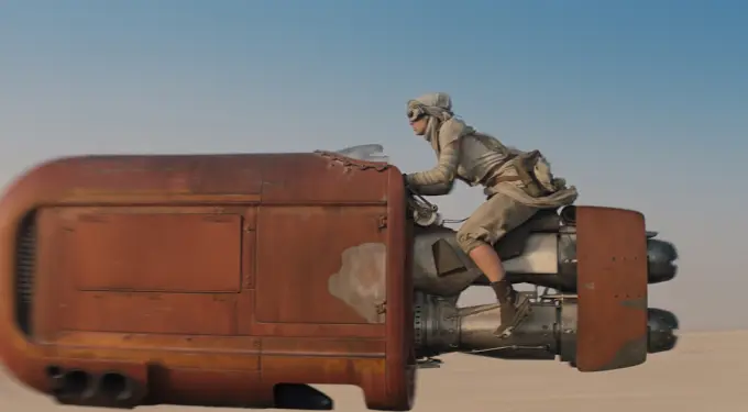 Daisy Ridley riding a speeder bike in desert scene from Star Wars