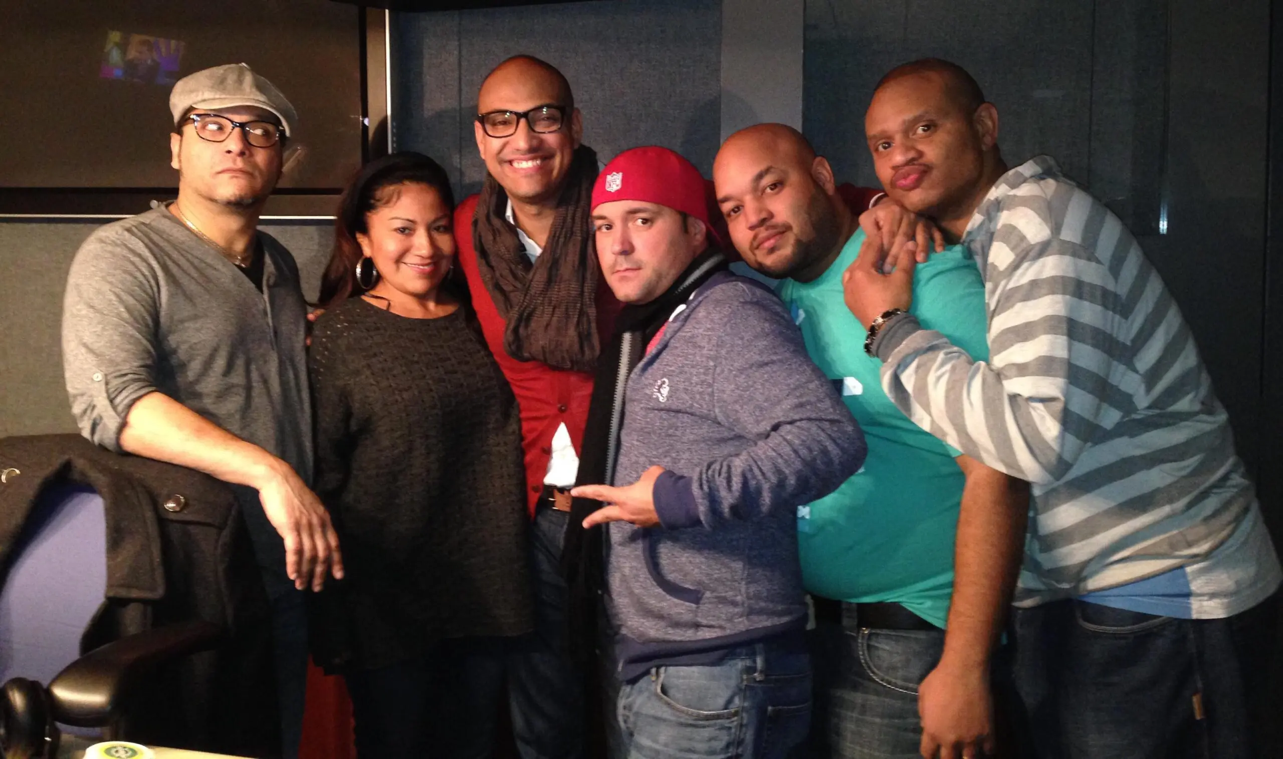 Six people posing together inside a radio studio