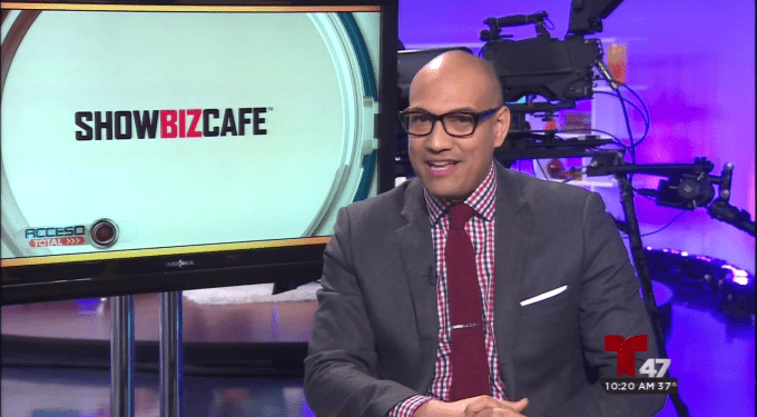 Man in suit and glasses on TV set with ShowBizCafe logo on screen