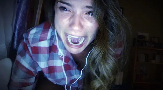 a woman screams at a webcam wearing a plaid shirt and earphones