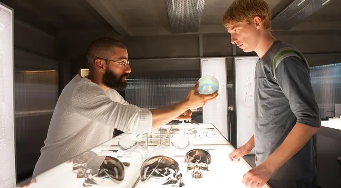 Oscar Isaac hands glowing orb to Domhnall Gleeson in futuristic lab scene