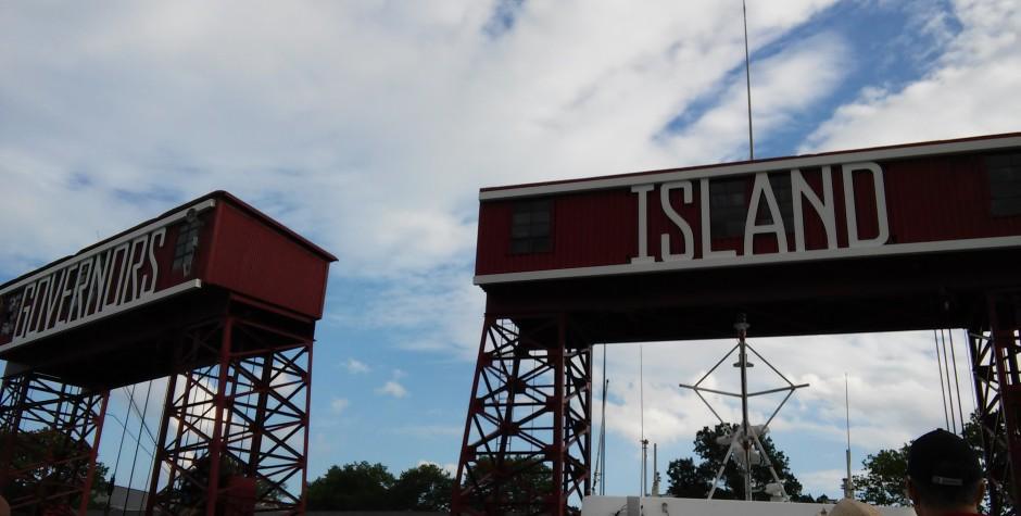 Red metal structures display the Governors Island sign against cloudy weather.
Red metal structures with Governors Island signs under cloudy sky
